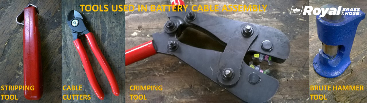 A selection of tools used in battery cable assembly, each labeled with its specific function. From left to right, the tools include a red-handled stripping tool, a pair of red-handled cable cutters, a crimping tool with red handles, and a blue brute hammer tool. These tools are arranged on a wooden surface, showcasing their importance in the assembly process. The text at the top of the image reads "TOOLS USED IN BATTERY CABLE ASSEMBLY," with the Royal Brass and Hose logo visible in the top right corner.